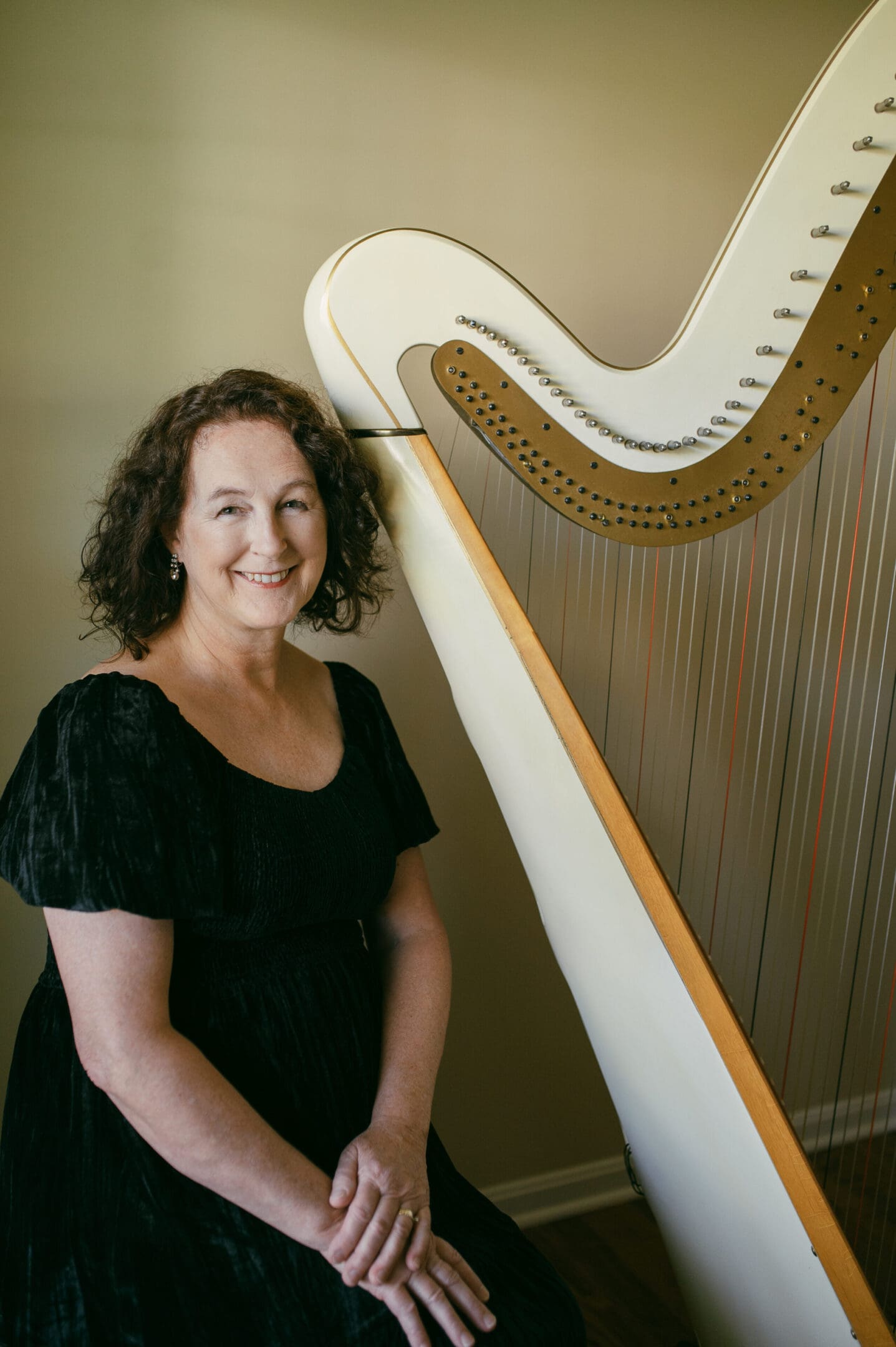 Woman smiling next to a large harp.